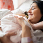 Mother breastfeeding newborn in hospital ward