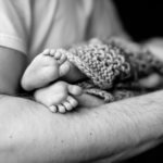 greyscale baby feet in father's hands