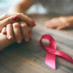 female hands and symbol of breast cancer awareness