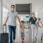 Masked family with suitcase walking through airport