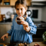 Little girl frosting a cupcake