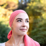 celebrating breast cancer awareness week featured image - Woman with cancer wearing a pink scarf looking optimistic