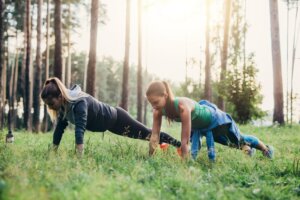 Two female friends doing push-up exercise training outdoors how to train for backpacking