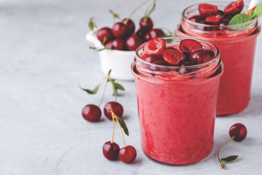 Cherry smoothie in glass jars with mint leaves and fresh berries
