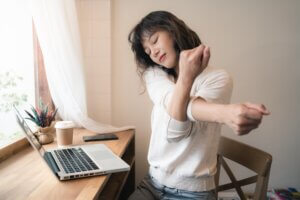 Young Asian woman taking shot break and stretching while working from home. 