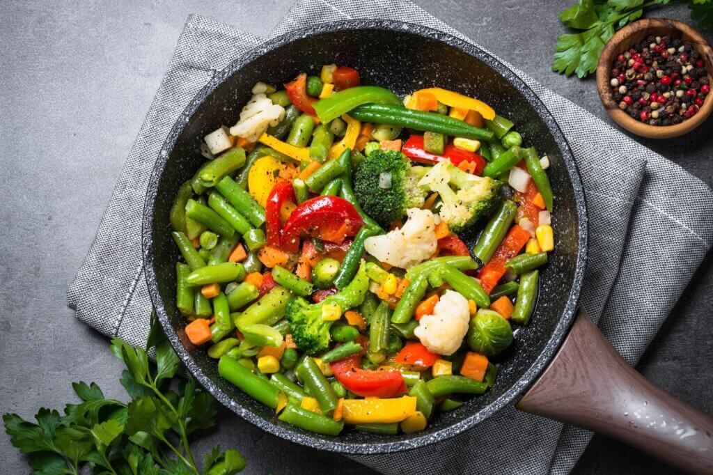 Stir fry vegetables in the wok on black table. Healthy vegan food. Low-calorie dish. Top view.