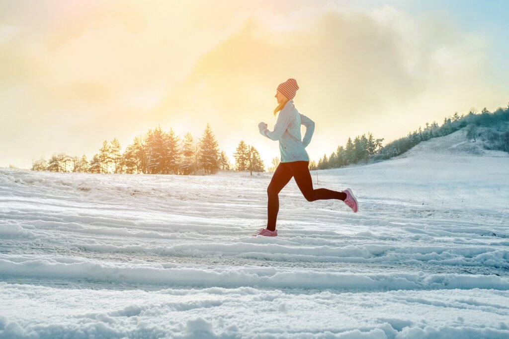 Running woman. Runner on the snow in winter sunny day. Female fitness training outdoors.