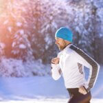 young fit man jogging in the snow exercising during the winter