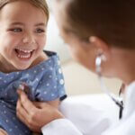 Happy child, girl and stethoscope of doctor for medical consulting, healthy lungs and listening to heartbeat. Face of laughing kid, pediatrician and chest assessment for healthcare analysis in clinic. a simple thank you